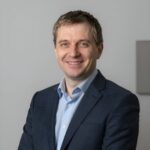 Портрет уверенного российского бизнесмена с дружелюбным взглядом на размытом нейтральном фоне в студии